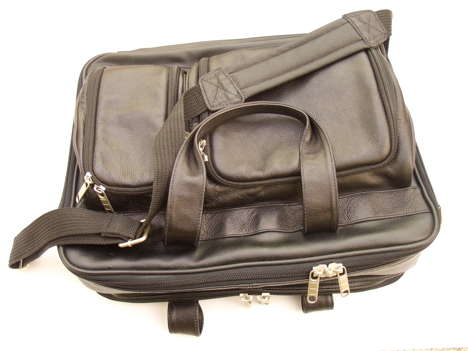 Black leather briefcase with zippered pockets, handles and shoulder strap seen from above on white