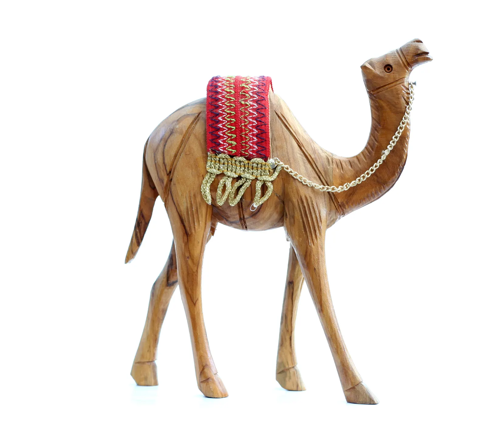 Carved wooden camel figurine with red woven saddle and gold chain on a white background