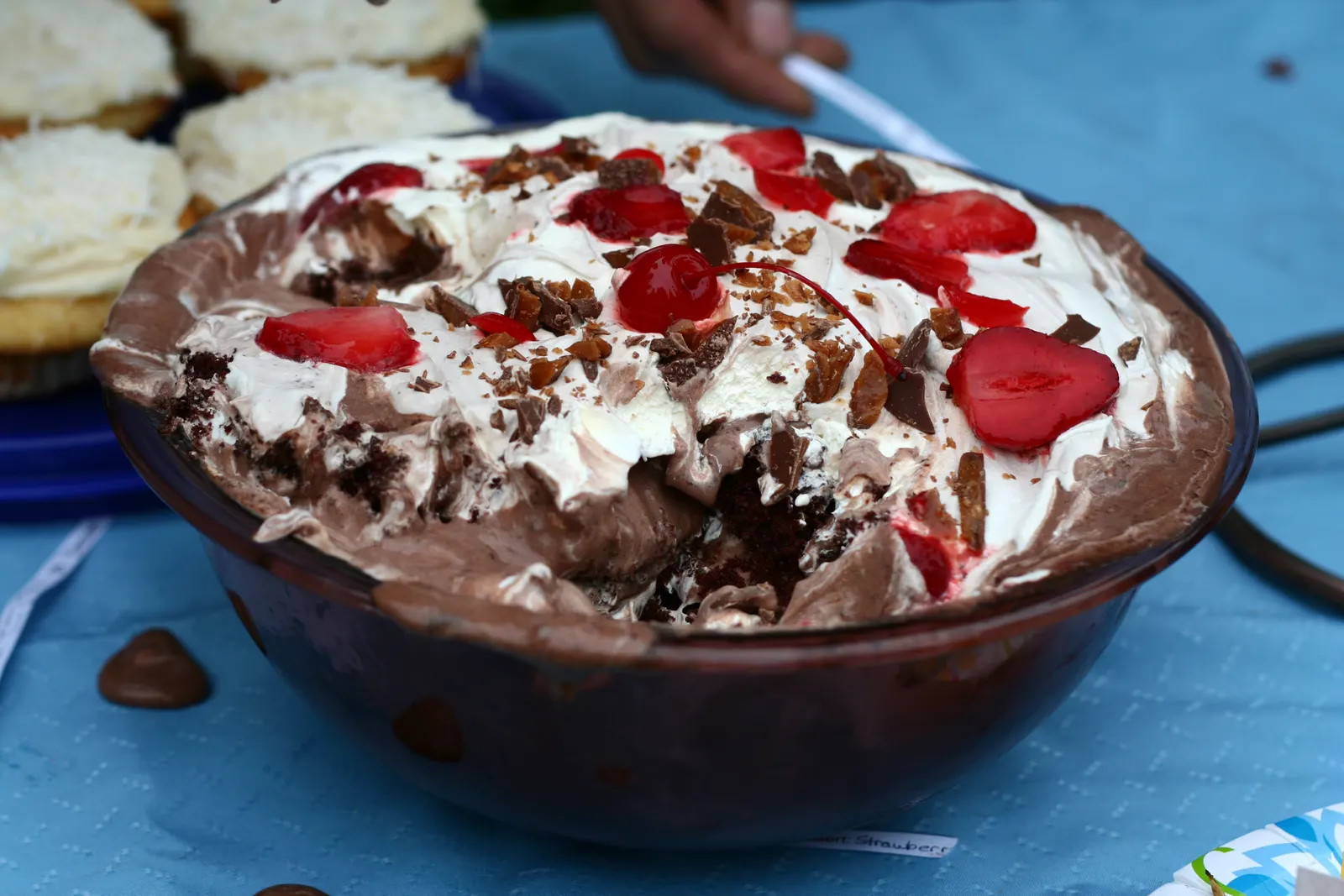Chocolate trifle with whipped cream, strawberries and chocolate shavings in a glass bowl