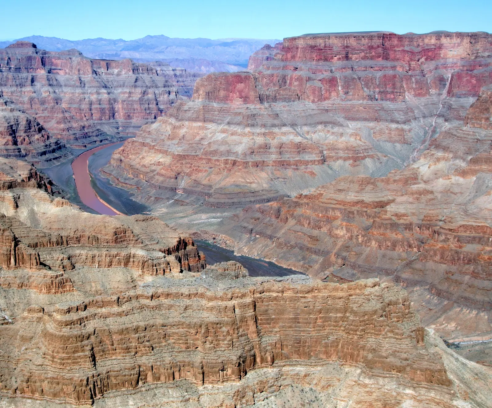 Aerial view of the Grand Canyon's layered red cliffs with the river winding through