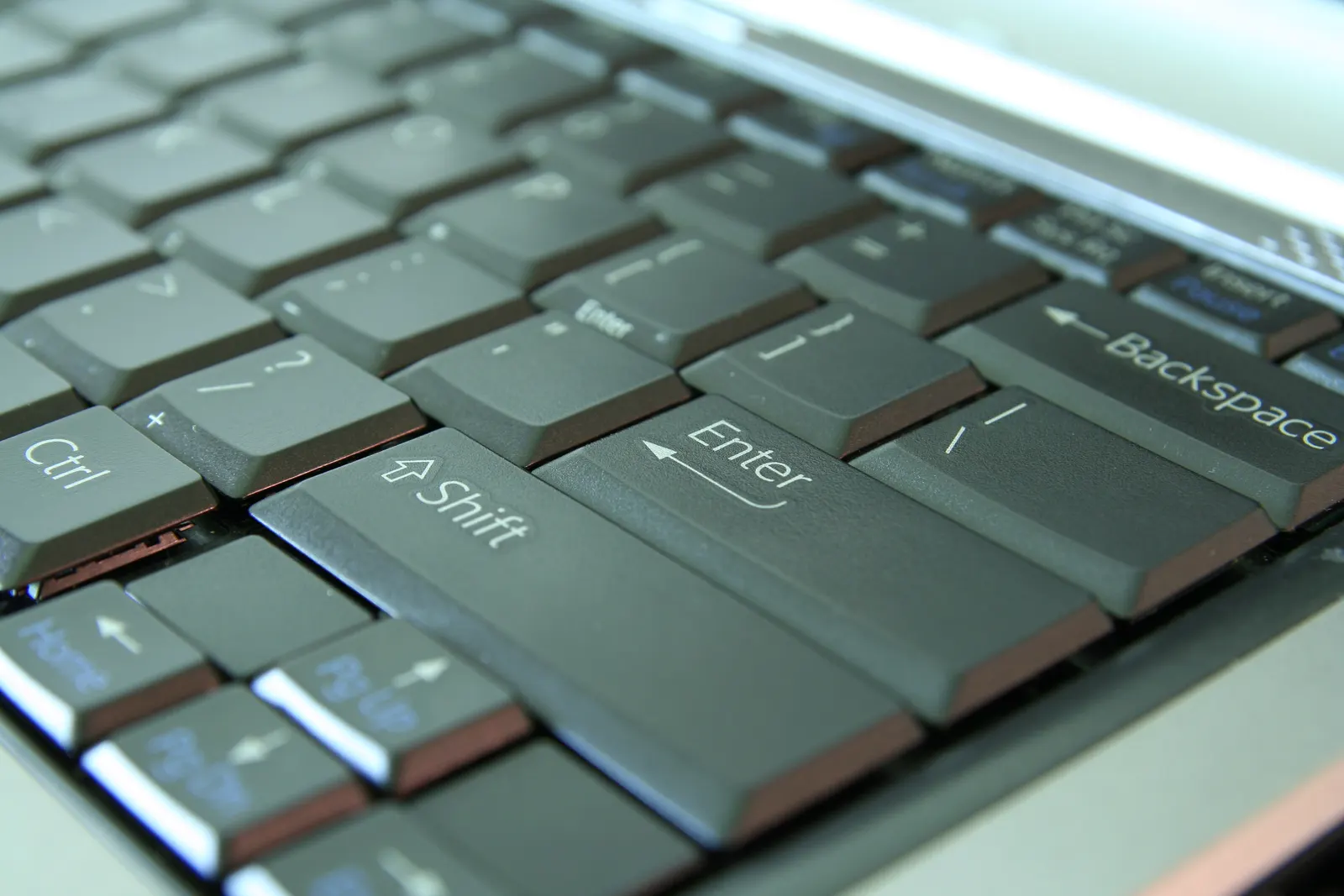 Angled close-up of laptop keyboard keys including Shift, Enter and Backspace