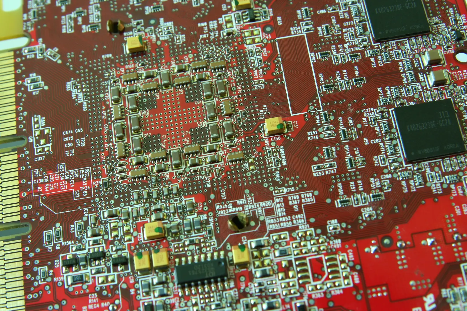 Close-up of a red printed circuit board with chips, capacitors and gold edge connector