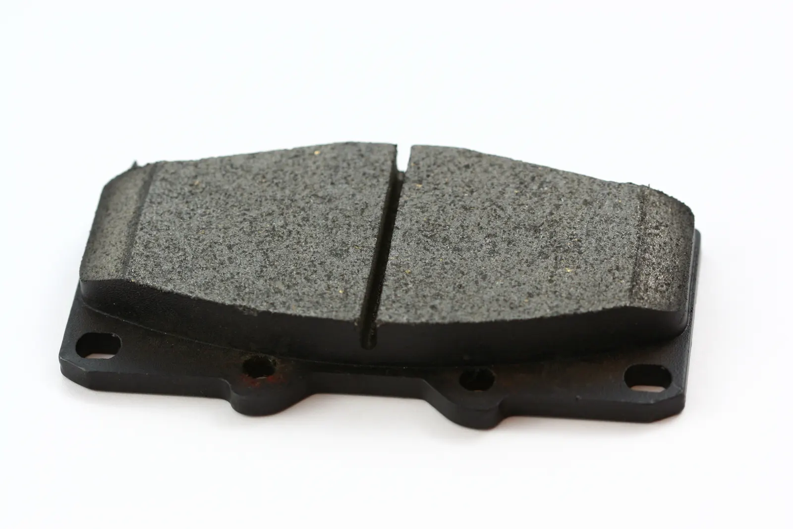 Black disc brake pad with metal backing plate on a white background