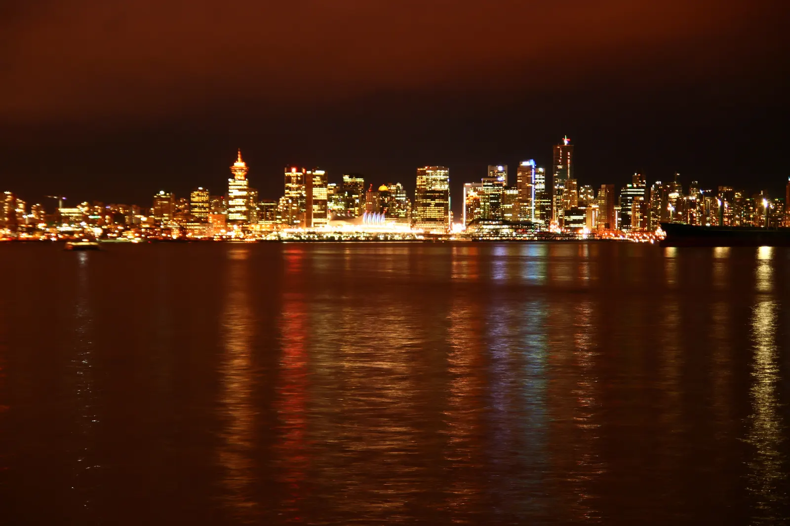 Vancouver city skyline lit up at night with colourful reflections on the water