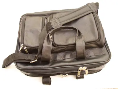 Black leather briefcase with zippered pockets, handles and shoulder strap seen from above on white