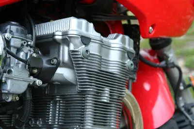 Close-up of a finned silver motorcycle engine beside a glossy red fuel tank