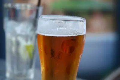 Glass of amber beer with foam and condensation beside a blurred glass of water