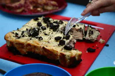 Cookies and cream cheesecake on a red board with a fork lifting a piece