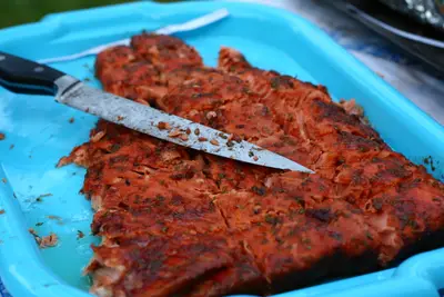 Grilled glazed salmon fillet with a knife on a turquoise serving tray