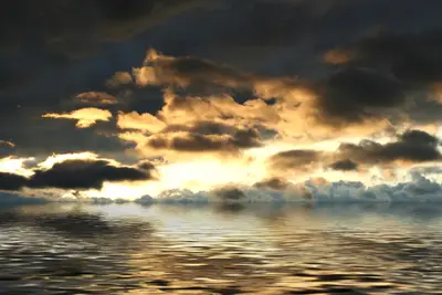 Golden sunset light breaking through dark clouds over rippling ocean water