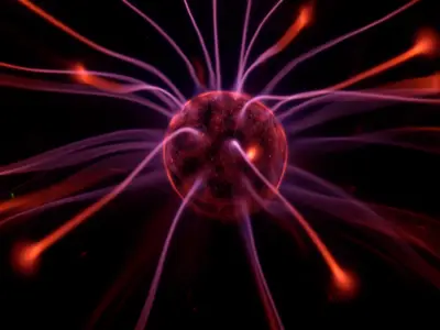 Plasma ball with purple and red electric tendrils radiating on a black background