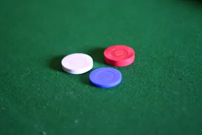 Red, white and blue poker chips sitting on green felt