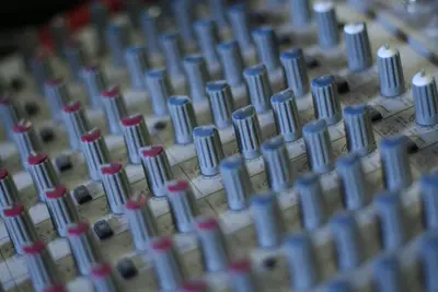 Rows of grey and red knobs on an audio mixing console in shallow focus
