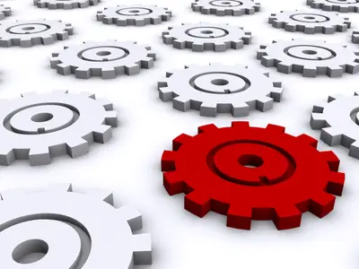 One red 3D gear surrounded by rows of grey gears on a white background