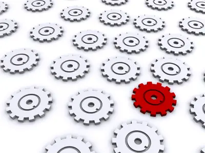 One red 3D gear among many white gears on a white surface