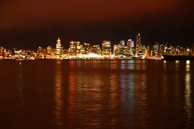 Vancouver city skyline lit up at night with colourful reflections on the water